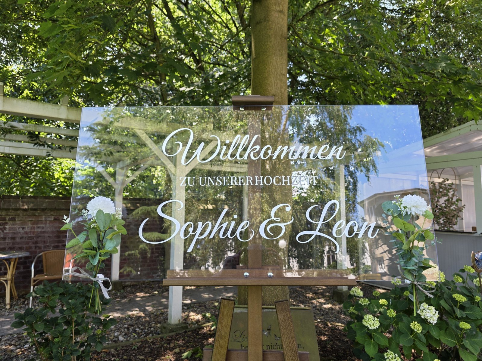 Individuell gestaltetes transparentes Hochzeitsschild auf einer Staffelei